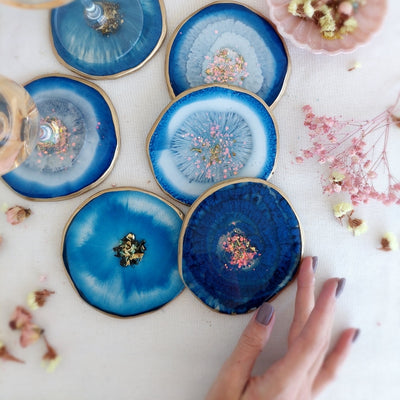 Blue pigment paste for epoxy resin art, showcasing vibrant coasters with gold accents.