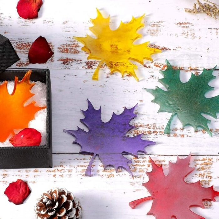 Silicone mold shaped like maple leaves in various colors on a rustic wooden surface.